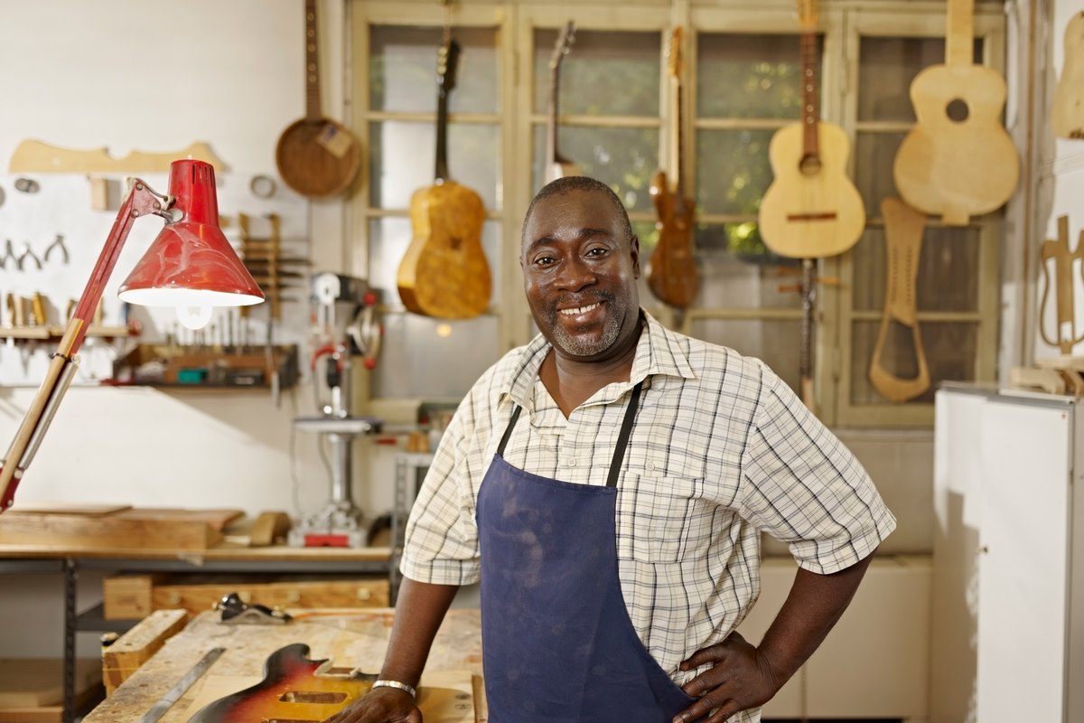 A New Haven woodworker standing in his workshop beside handmade instruments